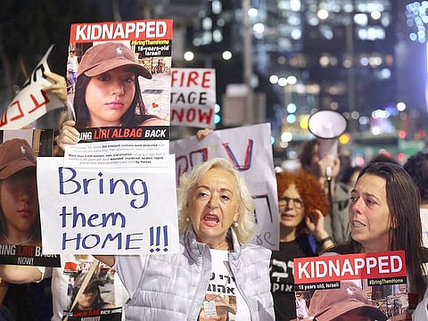 Relatives and supporters of hostages held in Gaza since Hamas's October 7 attack on Israel hold placards and an image of 18-year-old Liri Albag during a demonstration outside the defence ministry in Tel AViv calling for a deal to be made by the Israeli government for their release, on November 15, 2023.