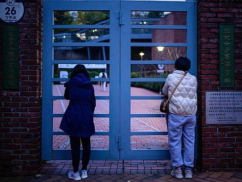 Relatives stand outside the school gates after dropping their children to sit for the annual college entrance exam, known locally as Suneung, outside the Ehwa Girls Foreign Language High School in Seoul.