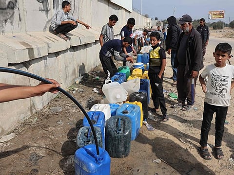 Palestinian children fill containers with water in Rafah, in the southern Gaza Strip on November 13, 2023, amid water shortage.