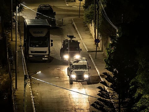 Israeli military vehicles drive down a road during a raid in the occupied West Bank Jenin refugee camp