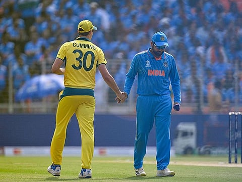 India's captain Rohit Sharma and as his Australia's counterpart Pat Cummins (L) shake hands during the toss before the start of the 2023 ICC Men's Cricket World Cup one-day international (ODI) final match between India and Australia at the Narendra Modi Stadium in Ahmedabad.