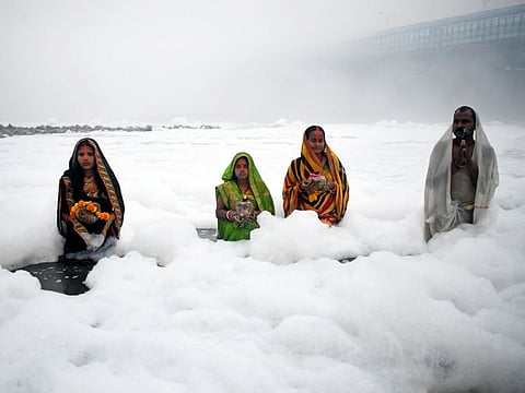 Devotees offer prayers to the rising sun on the banks of polluted Yamuna river on the last day of Chhath Puja festival, at Kalindi Kunj, in New Delhi on Monday, November 20, 2023.