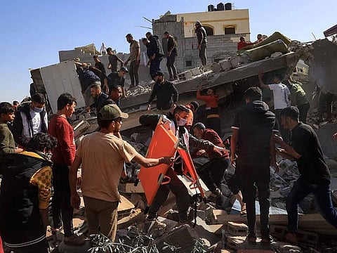 A Palestinian medic walks among civilians on the rubble of a building after an Israeli strike on Rafah, in the southern Gaza Strip on November 23, 2023, amid continuing battles between Israel and the Palestinian militant group Hamas.