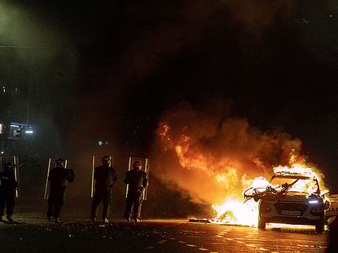 Riot police officers face down demonstrators next to a burning police car near a crime scene of a school stabbing that left several children and adults injured, in Dublin, Ireland, November 23, 2023. REUTERS/Clodagh Kilcoyne