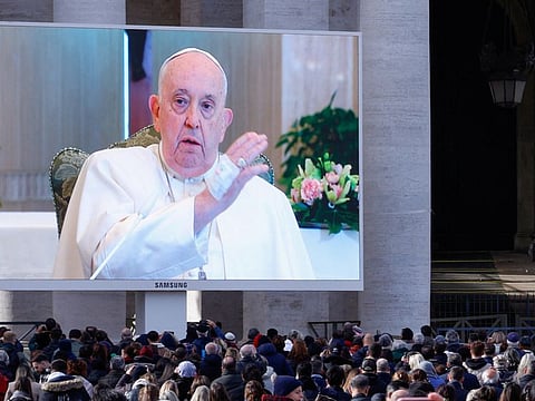 Pope Francis blesses faithful as he appears on a screen in St. Peter's Square, while leading the Angelus prayer from Santa Marta chapel at the Vatican, on November 26, 2023.