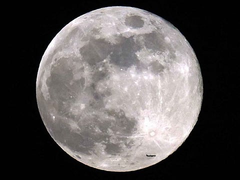 A passenger aircraft flies before the rising beaver moon. The 'beaver' moon moniker, passed down from Native American lore, corresponds to the time of the year when beavers are more active.