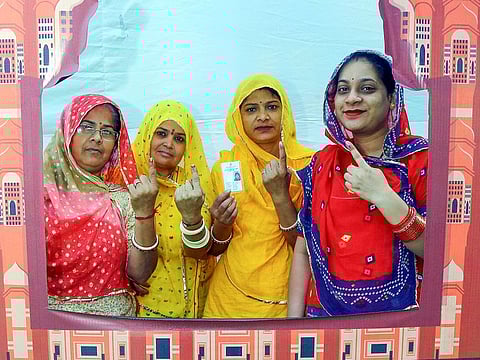 Women voters show their ink-marked fingers as they pose for a picture at the photo booth after casting their vote for the Rajasthan Assembly Elections, in Jaipur on Saturday