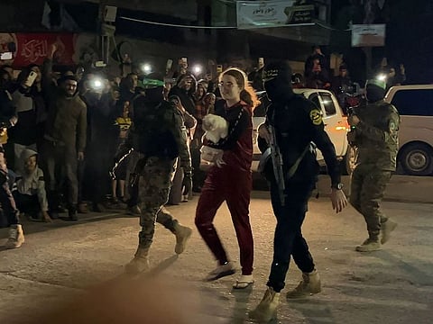 Hamas militants accompany a newly released Israeli hostage, held since the Hamas' October 7 attacks, before handing them over to the Red Cross in Rafah, in the southern Gaza Strip on November 28, 2023.