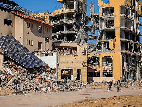 Palestinians ride bicycles by destroyed buildings in Gaza City on Wednesday, Nov. 29, 2023