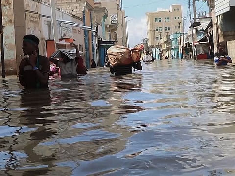 In this image made from video, men walk through floodwaters on a street in the town of Beledweyne, in Somalia.