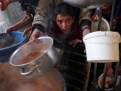 People gather to get their share of charity food offered by volunteers, amid food shortages, as the conflict between Israel and the Palestinian Islamist group Hamas continues, in Rafah, in the southern Gaza Strip.