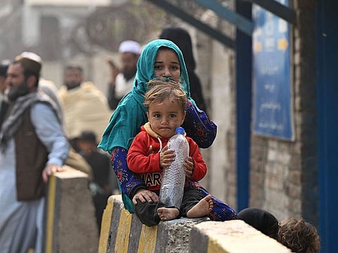 Afghan refugee children sitting outside the United Nations High Commissioner for Refugees (UNHCR) Azakhel Voluntary Repatriation Centre in Nowshera.