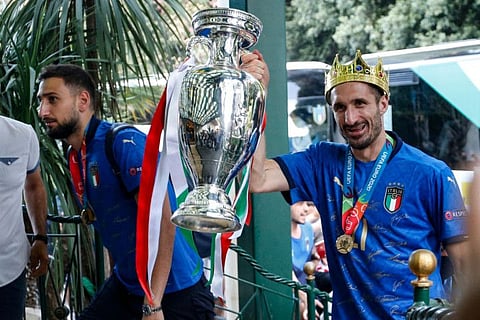 Italy's captain Giorgio Chiellini (right) carrying the trophy next to goalkeeper Gianluigi Donnarumma as Italy's football team arrive on July 12, 2021 at Parco dei Principi hotel in Rome.