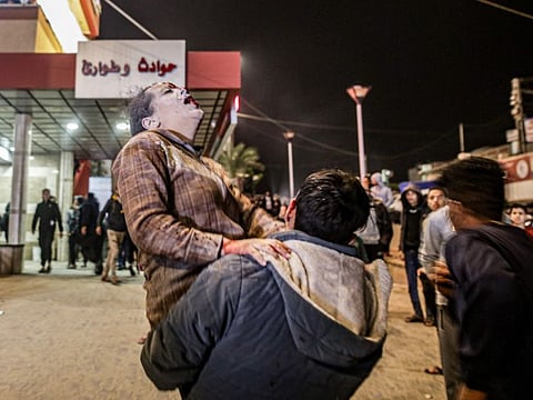 A man carrying a woman, injured following Israeli bombardment, arrives at Nasser hospital in Khan Younis in the southern Gaza Strip on December 17, 2023.