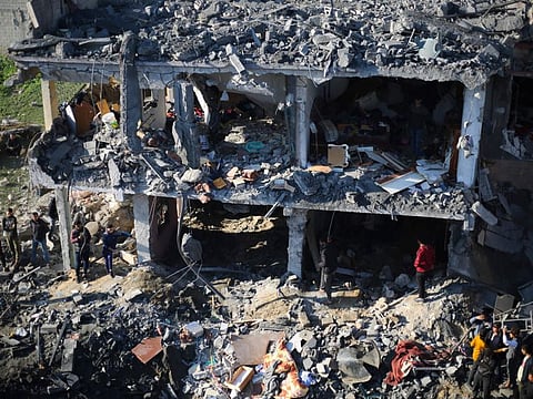 Palestinians watch the destruction after the Israeli bombardment of the Gaza Strip outside a morgue in Rafah, on December 19, 2023.