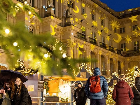 People stroll past Christmas lights and decorations
