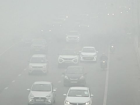 Vehicles ply on a road amid dense fog on a cold winter morning, in New Delhi on Wednesday.