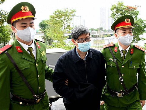 Vietnam's former minister of health Nguyen Thanh Long (C) is led into a court by police for his anti-corruption trial over Covid test kit production bribes in Hanoi on January 3, 2024.