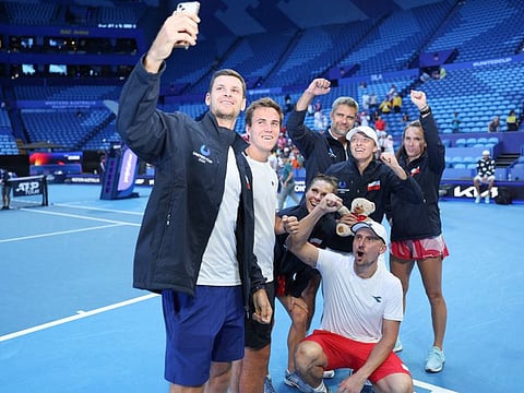 Poland's Hubert Hurkacz (left), Daniel Michalski (2nd left), Jan Zielinski (bottom), Katarzyna Kawa, Iga Swiatek (2nd right), Captain Tomas Wiktorowski and Kataryzna Piter (centre) pose for a selfie on the court after progressing to the semi-final of the United Cup tennis tournament in Perth on Wednesday.