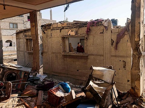 A child looks through the window of a destroyed house on January 5, 2024, following Israeli bombardment in Rafah, on the southern Gaza Strip, amid continuing battles between Israel and the Palestinian militant group Hamas.