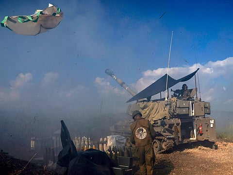 An Israeli soldier wearing a patch on the back of his flack jacket showing Lebanon's Hezbollah leader Hassan Nasrallah as a target, stands in front of a tank in Upper Galilee in northern Israel, as an artillery unit shells southern Lebanon on January 4, 2024. Nasrallah warned Israel against all-out conflict, after Israeli army chief Herzi Halevi, in a visit to the Lebanese border, said troops were "in very high readiness".