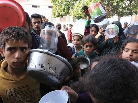 Displaced Palestinians wait to receive free food from a volunteer-run hospice near Nasser Medical Hospital in Khan Younis, southern Gaza, on January 9, 2024.