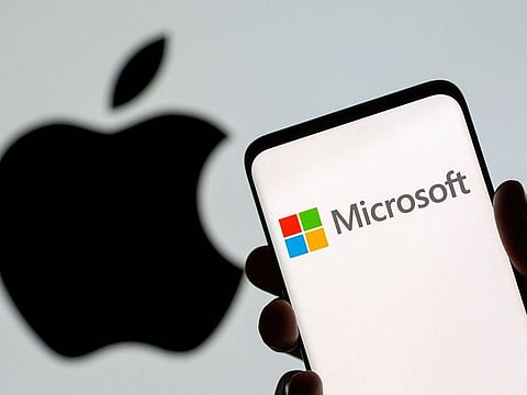Microsoft logo is seen on the smartphone in front of displayed Apple logo in this illustration .
