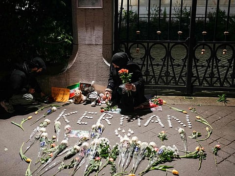 A woman holds flowers during a gathering in tribute to victims in front of the Iranian Embassy in Paris.