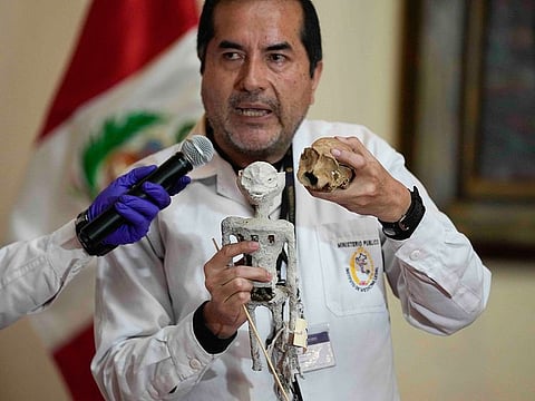 Forensic archaeologist Flavio Estrada from Peru's prosecutor's office shows a doll, which was seized by authorities before it was shipped to Mexico, during a press conference.