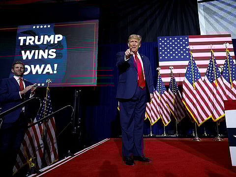 Republican presidential candidate and former US President Donald Trump gestures as his son Eric Trump applauds next to him during his Iowa caucus night watch party in Des Moines, Iowa, U.S., January 15, 2024.