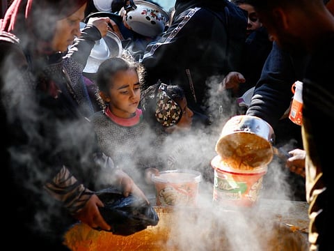 Palestinians wait to receive food cooked by a charity kitchen amid shortages of food supplies, amid the ongoing conflict between Israel and the Palestinian Islamist group Hamas, in Rafah in the southern Gaza Strip, January 16, 2024.