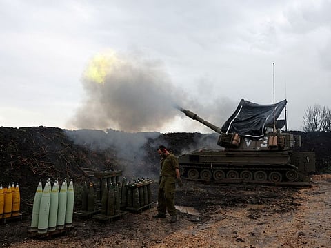 An Israeli soldier stands by, as a mobile artillery unit fires, near the Israel-Lebanon border, in northern Israel.