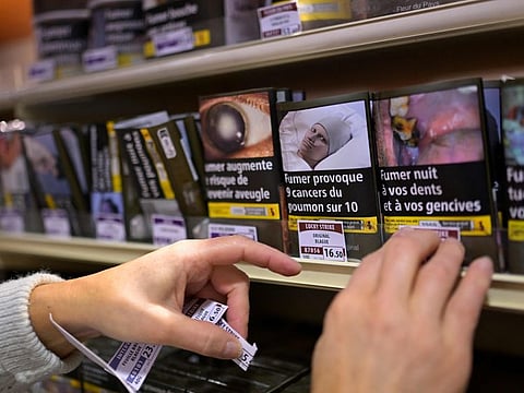 A shop worker updates tobacco price labels as Saudi Arabia restricts tobacco shops near schools and mosques.