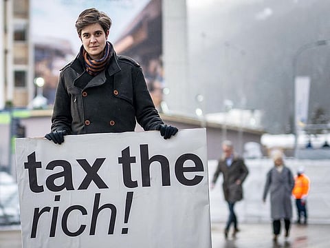 Austrian Marlene Engelhorn, who inherited from her family who owns the Germany's chemical giant BASF, poses with a placard reading "Tax the rich!" at the entrance of the Congress centre on the opening of the annual meeting of the World Economic Forum (WEF) in Davos, on January 15, 2024.