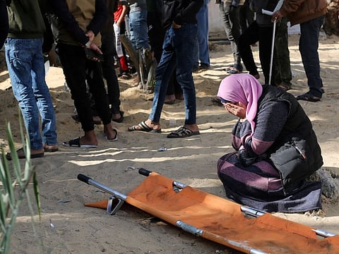 A woman reacts while people bury bodies of Palestinians killed in an Israeli strike, on the Nasser hospital premises as Palestinians cannot reach the cemetery due to the Israeli ground operation, in Khan Younis in the southern Gaza Strip, on January 22, 2024.