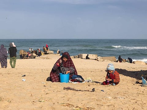 A woman washes clothes in a bucket at a makeshift tent camp for displaced Palestinians in Rafah near the border with Egypt in the southern Gaza Strip, on January 24, 2024.