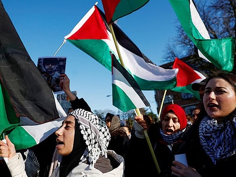 People hold flags during a pro-Palestinian demonstration outside the International Court of Justice (ICJ) as judges rule on emergency measures against Israel following accusations by South Africa that the Israeli military operation in Gaza is a state-led genocide, in The Hague, Netherlands, on January 26, 2024.