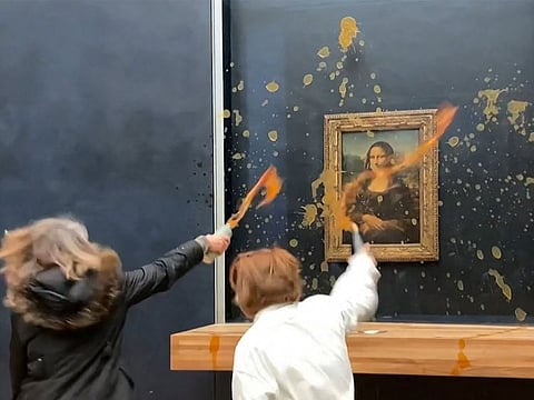 Two environmental activists from the collective dubbed "Riposte Alimentaire" (Food Retaliation) hurling soup at Leonardo Da Vinci's "Mona Lisa" (La Joconde) painting, at the Louvre museum in Paris.