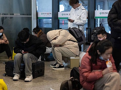 People sit with their luggage at Wuhan Railway Station after some trains were suspended due to freezing rain and snow, in Wuhan in central China's Hubei province.