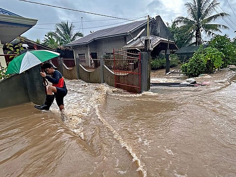 A man wades through floodwaters brought about by heavy rains at a residential neighbourhood in Propseridad town, Agusan del Sur province on southern Mindanao island.