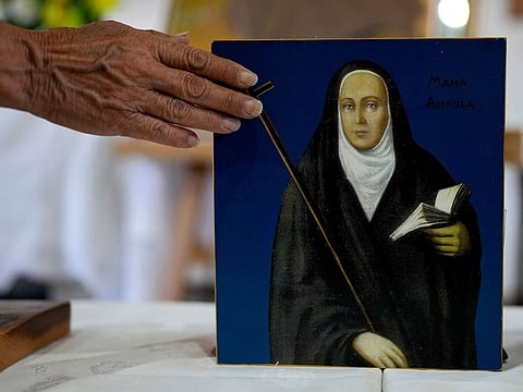 A devotee touches a painting depicting María Antonia de Paz y Figueroa, more commonly known by her Quechua name of “Mama Antula,” on the outskirts of Buenos Aires, Argentina.