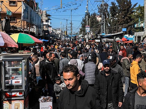People walk along a crowded main street in Rafah in the southern Gaza Strip. Nearly the last place spared an Israeli offensive so far, Rafah’s population has more than quintupled with Palestinians streaming in to escape fighting. They pack by the dozens into apartments. Sidewalks and once-empty lots are clogged with tents full of families.