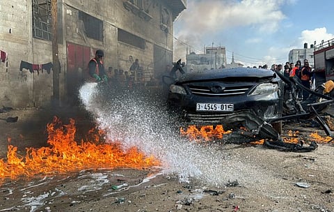 A firefighter extinguishes a burning car hit by an Israeli strike in Rafah in the southern Gaza Strip, on February 10, 2024.