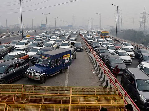 Vehciles move at snail pace after police barricade a major highway at Ghazipur near New Delhi to stop thousands of protesting farmers from entering the capital, India, Tuesday, Feb.13, 2024.