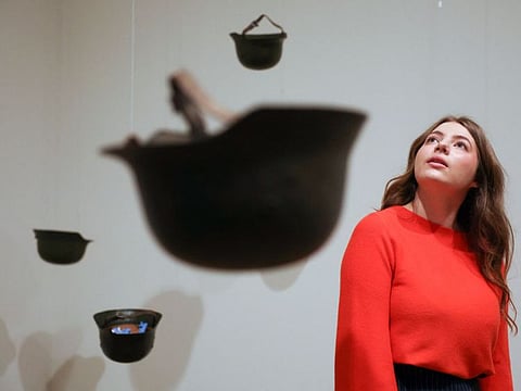 A gallery employee poses with an artwork entitled 'Helmets (Pieces of Sky)' 2001, by Yoko Ono, during a photocall to promote the forthcoming exhibition 'Yoko Ono: Music of the Mind' at Tate Modern in London on February 13, 2024.