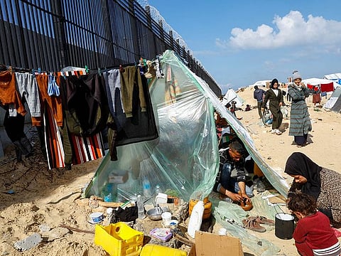 Displaced members of Palestinian Abu Mustafa family, who fled their house due to Israeli strikes, prepare food as they shelter at the border with Egypt, in Rafah in the southern Gaza Strip, February 10, 2024.