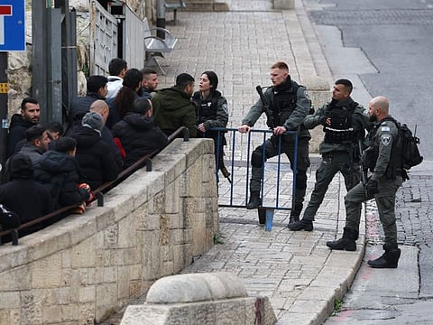 A member of the Israeli security forces checks identity cards as worshippers wait at a checkpoint near Lion's Gate to enter the Al Aqsa Mosque compound before the Friday noon prayer, in Jerusalem on February 16, 2024.