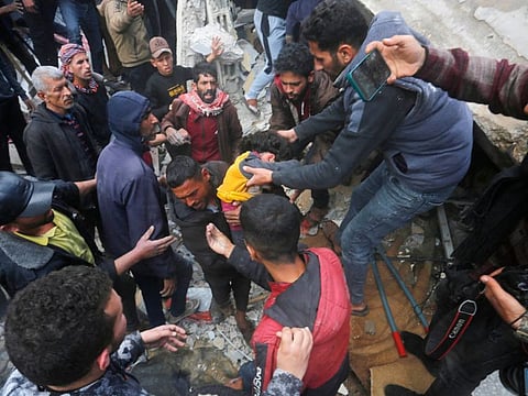 People pull a child from the rubble of the Baraka family home in Deir Al Balah in the central Gaza Strip after it was hit in an Israeli air strike on February 18, 2024.