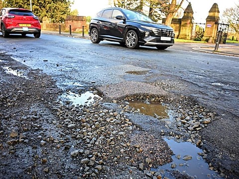 A car is driven past a pothole in a damaged road in Liverpool, north west England on January 30, 2024.