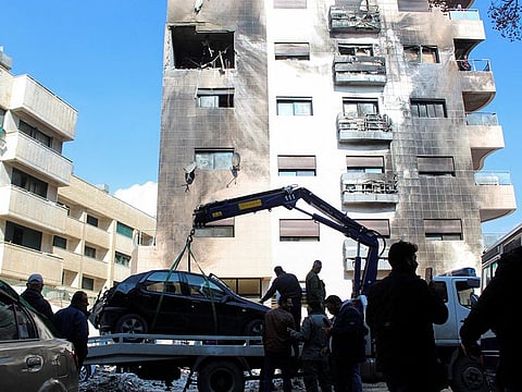 Workers and people at the damaged building after, according to Syrian state media reports, several Israeli missiles hit a residential area in the Kafr Sousa district, on February 21, 2024.